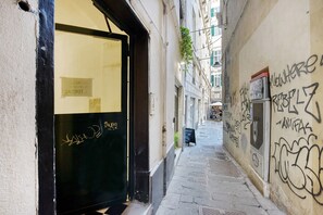 A narrow alleyway with a building entrance, graffiti on the walls, and a signboard. - 'Bright Genova' Apartment with Wi-Fi and Air Conditioning (Genova)
