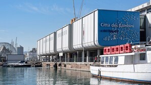 Un edificio frente al agua con un gran letrero azul que dice 'Citta dei Bambini'.
