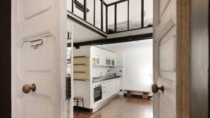 Cocina con armarios blancos, encimera de madera y una banca.