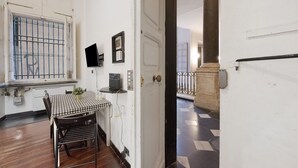 Una habitación con una mesa a cuadros, una ventana con barrotes, una puerta y un piso de baldosas.