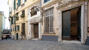Una estrecha calle empedrada con edificios históricos, una entrada visible con una reja de metal y una puerta con superficie texturizada.