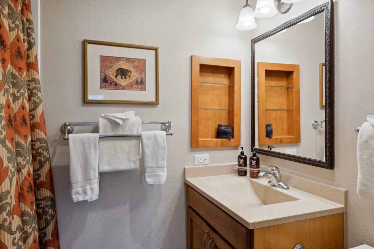 A bathroom with a sink, mirror, towel rack, and a framed picture on the wall.