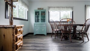 A dining area with a wooden table and chairs, a teal cabinet, and a rustic wooden structure.
