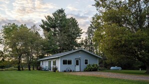 A single-story house with a gabled roof, a front porch with a bench, and a small front yard.