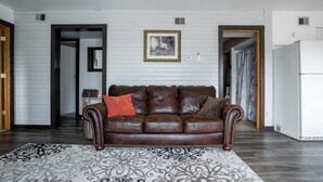 A living room with a brown leather sofa, a patterned rug, and a framed picture on the wall.