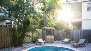 Ein Garten mit Swimmingpool, Holzterrasse und Gartenmöbeln.
