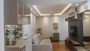 A modern living room with a sofa, a coffee table, a TV, and a ceiling fan. - Feet in the sand - near Beto Carrero (Barra Velha)