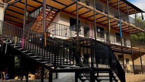 A multi-level building with a wooden deck and metal railings. - Debatoun (Debet)