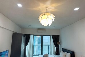 A hotel room with a bed, a ceiling light fixture, and a view of the outside. - Summer Suites KLCC by Luna (Kuala Lumpur)