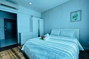A hotel room with a bed, a wardrobe, a mirror, and a wall-mounted plant. - Summer Suites KLCC by Luna (Kuala Lumpur)