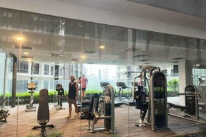 A gym with exercise equipment and a glass wall. - Summer Suites KLCC by Luna (Kuala Lumpur)