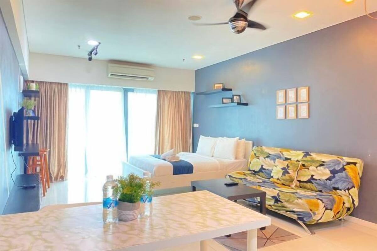 Une chambre d’hôtel avec un lit, un canapé, une table et un ventilateur de plafond.