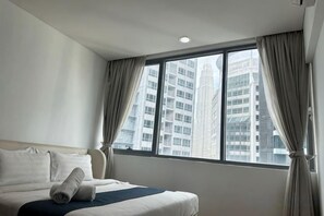 Une chambre d’hôtel avec un grand lit, une fenêtre avec des rideaux et une vue sur de hauts immeubles.