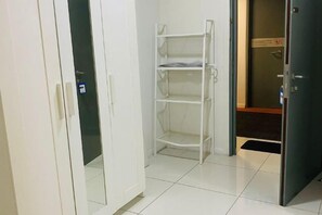 A room with a white wardrobe, a white shelving unit, and a door leading to a bathroom. - Summer Suites KLCC by Luna (Kuala Lumpur)