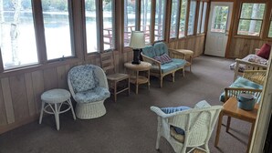 Ein gemütliches Zimmer mit Korbmöbeln, großen Fenstern und Seeblick.