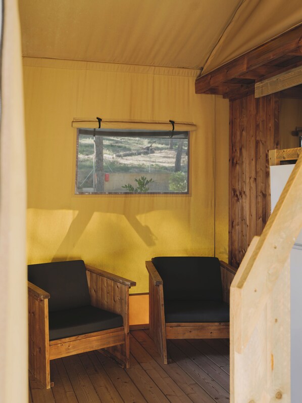 Una habitación con dos sillas de madera, una ventana que da a una zona verde y un techo de madera.