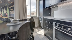 A modern kitchen with a dining area, including a table with chairs, a large window, and built-in appliances. - Perfect Located 2-bed Blue Mountains Getaway (Katoomba)