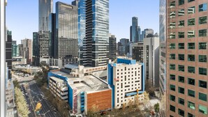 Un immeuble de grande hauteur doté d’une façade moderne en verre, entouré d’autres bâtiments imposants au cœur d’un paysage urbain.