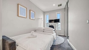 A hotel room with a bed, a desk, a chair, a TV, and a window. - Tranquil Apartment in Green, Well Connected Suburb (Canberra)