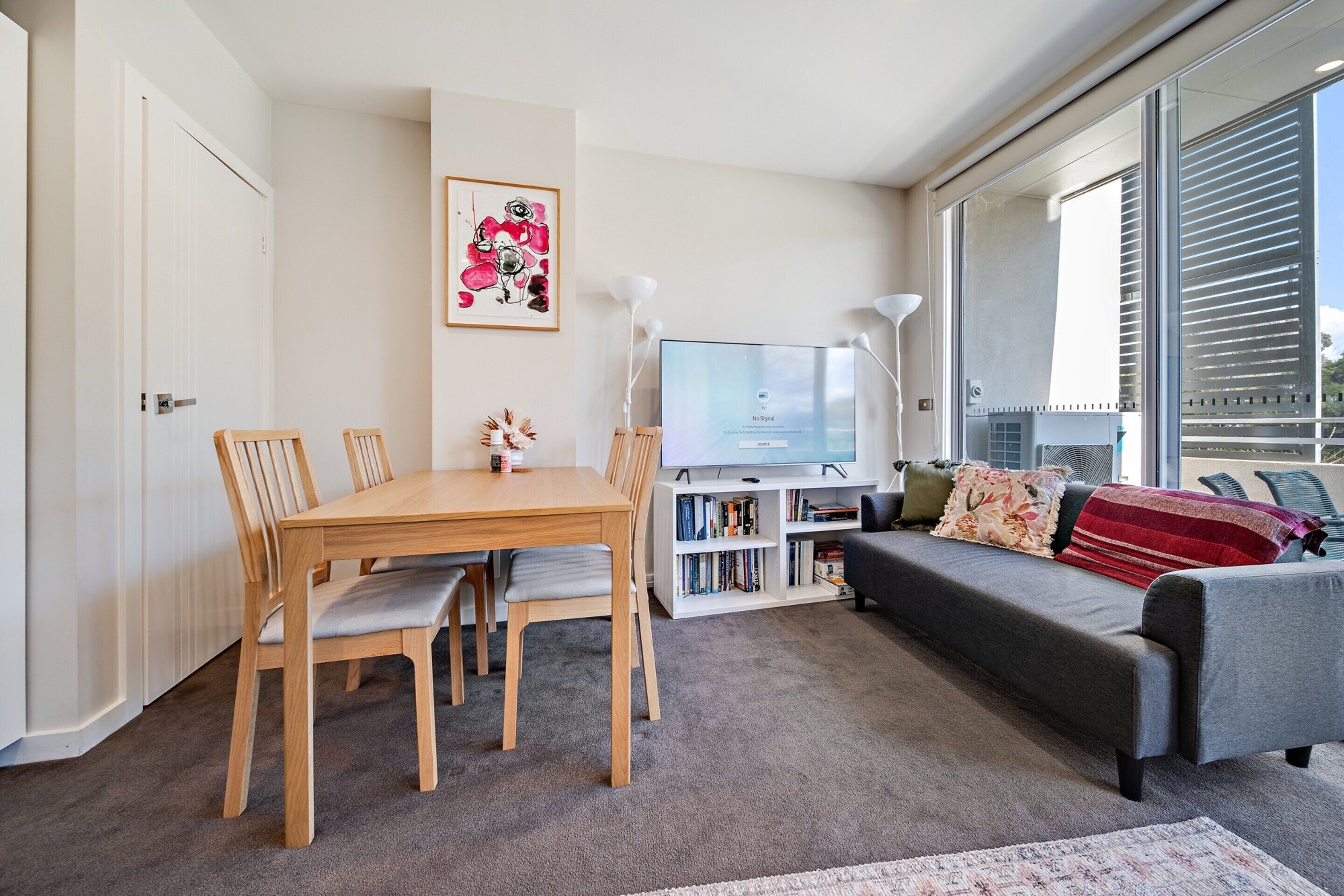 Un salon moderne comprenant une table à manger, des chaises, un canapé, un téléviseur et une bibliothèque.