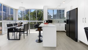 A modern kitchen with a large island, white cabinetry, and a black refrigerator. - Stylish 2-bed in Surfers Paradise With River Views (Gold Coast)