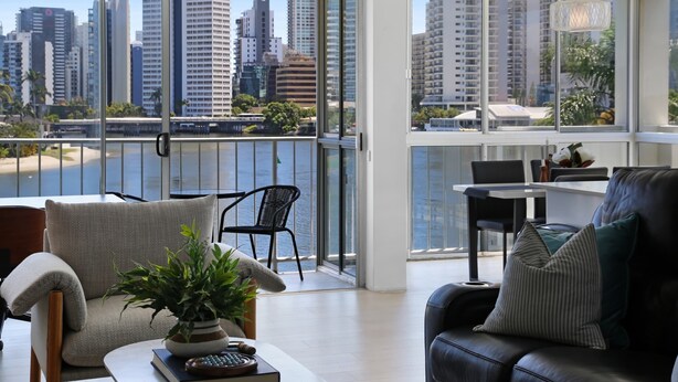A modern living room with a view of a city skyline and a body of water. - Stylish 2-bed in Surfers Paradise With River Views (Gold Coast)