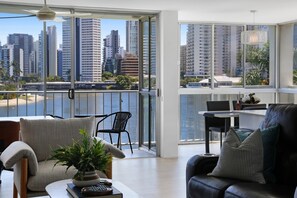 A modern living room with a view of a city skyline and a body of water. - Stylish 2-bed in Surfers Paradise With River Views (Gold Coast)