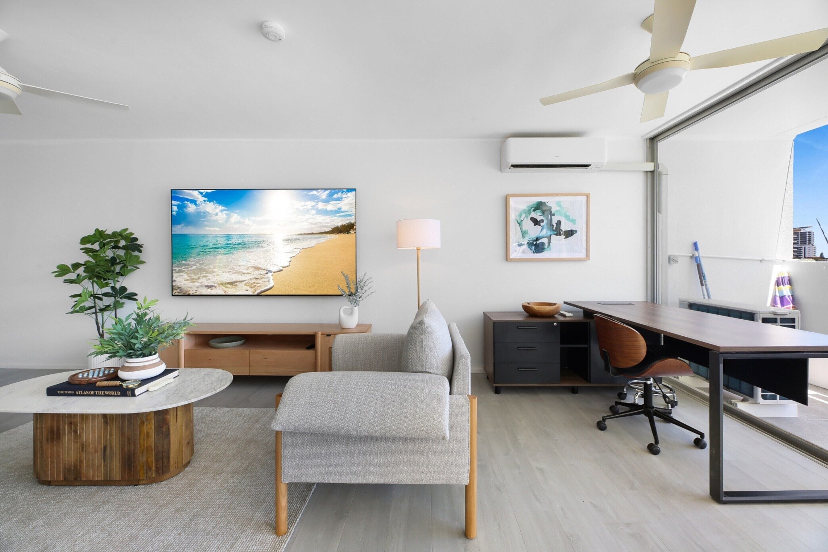 A modern living room with a large window, a desk, a comfortable sofa, and a coffee table.