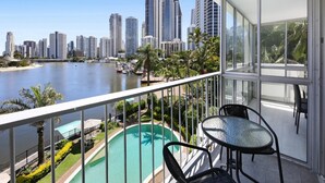 A balcony with a view of a city skyline, a swimming pool, and outdoor furniture. - Stylish 2-bed in Surfers Paradise With River Views (Gold Coast)
