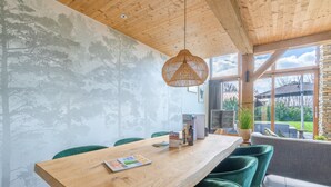 A dining area with a wooden table, green chairs, and a hanging light fixture. - Stylish Overnight Stay With a hot tub and Atmospheric Fireplace (De Koog)