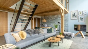 A modern living room with a grey sofa, wooden coffee table, and a staircase. - Stylish Overnight Stay With a hot tub and Atmospheric Fireplace (De Koog)