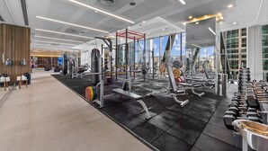 A modern gym with various exercise equipment, large windows, and a clean, spacious layout.