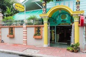 A building with a green archway entrance, a sign above the entrance, and a red mailbox on the right. - Samsen Sam Place (Bangkok)