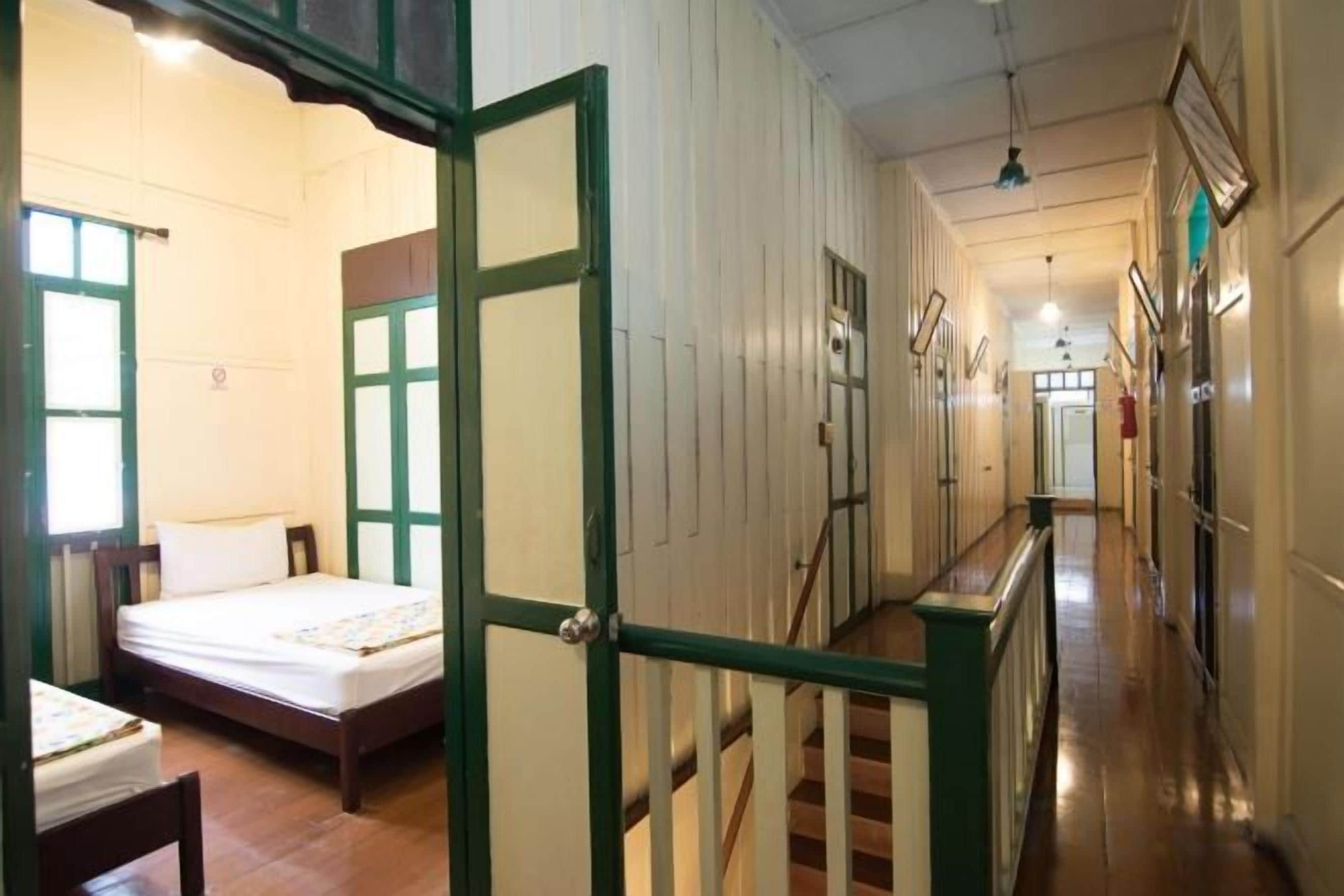 A hotel corridor with a bed, a staircase, and a door.