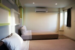 A hotel room with two beds, a window with curtains, an air conditioning unit, and a wall-mounted shelf. - Samsen Sam Place (Bangkok)
