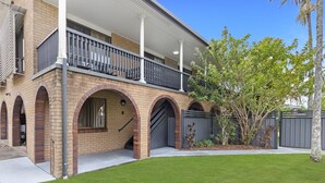 A two-story house with a balcony, brick arches, and a well-maintained lawn. - Spacious 3-bed Home With Large Balcony (Hervey Bay)