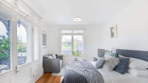 A bedroom with a bed, bedside tables, a window, and a view of the outside. - Perfect Located Studio Apartment (Sydney)