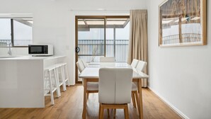 Eine moderne Küche mit weißer Arbeitsplatte, einer Mikrowelle und einem Essbereich mit weißem Tisch und Stühlen.