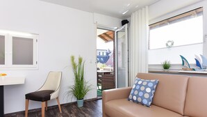 Een moderne woonkamer met een bank, een fauteuil, een bijzettafeltje en een potplant.