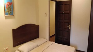 A single bed with a wooden headboard, a bedside table, and a nightstand. A door with a number is visible in the background. - Hotel Remix 2 Cameron Highlands (Brinchang)