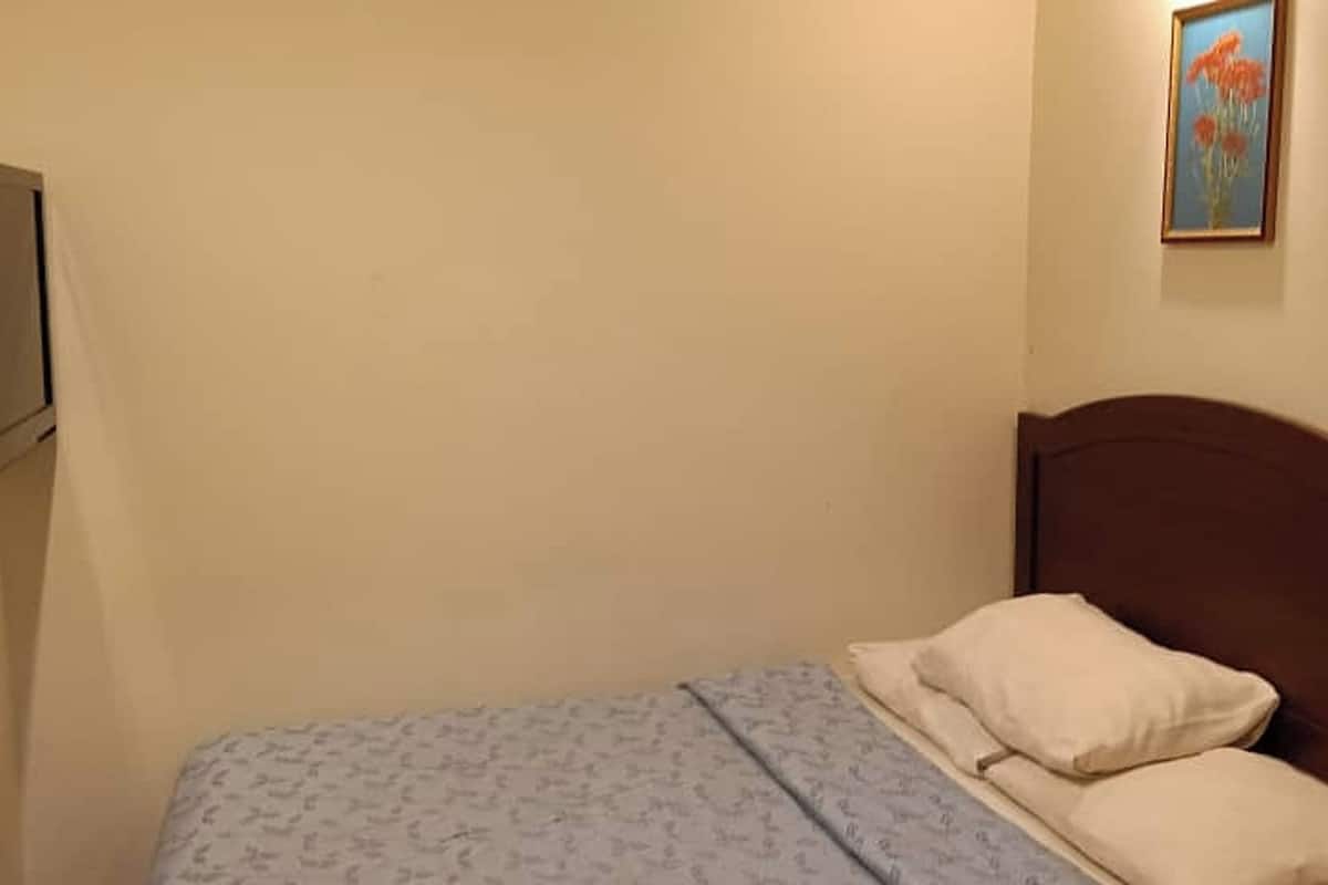 Ein Schlafzimmer mit Bett, Kissen, einem Nachttisch und einem gerahmten Bild an der Wand.
