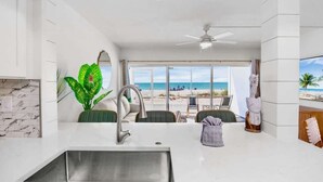 Una cocina moderna con un ventanal grande que da a una playa, un ventilador de techo y vistas al océano.