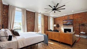 A room with a bed, a sofa, a fireplace, and a TV. - Stable #1 ~Walkable, BBQ, Fire Pits, Mini Golf (Louisville)