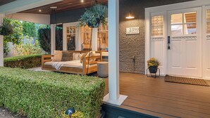 A covered outdoor seating area with a wooden bench, a hanging planter, and a door labeled "2390 LLOYD MOUNT". - Charming 4-Bedroom Home in Peaceful Parkside Setting with Hot Tub & Sauna (North Vancouver)
