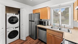 A compact kitchen with a washing machine, refrigerator, microwave, and dishwasher. - Ground Level Condo by Sunset High School (Portland)