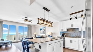 A modern kitchen with white cabinets, a central island, and a view of the ocean. - Laketown Wharf 1213 (Panama City Beach)