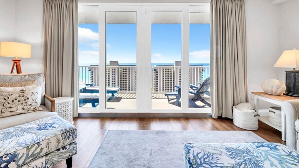 A hotel room with a balcony, a bed, a sofa, a desk, and a lamp. - Laketown Wharf 1213 (Panama City Beach)