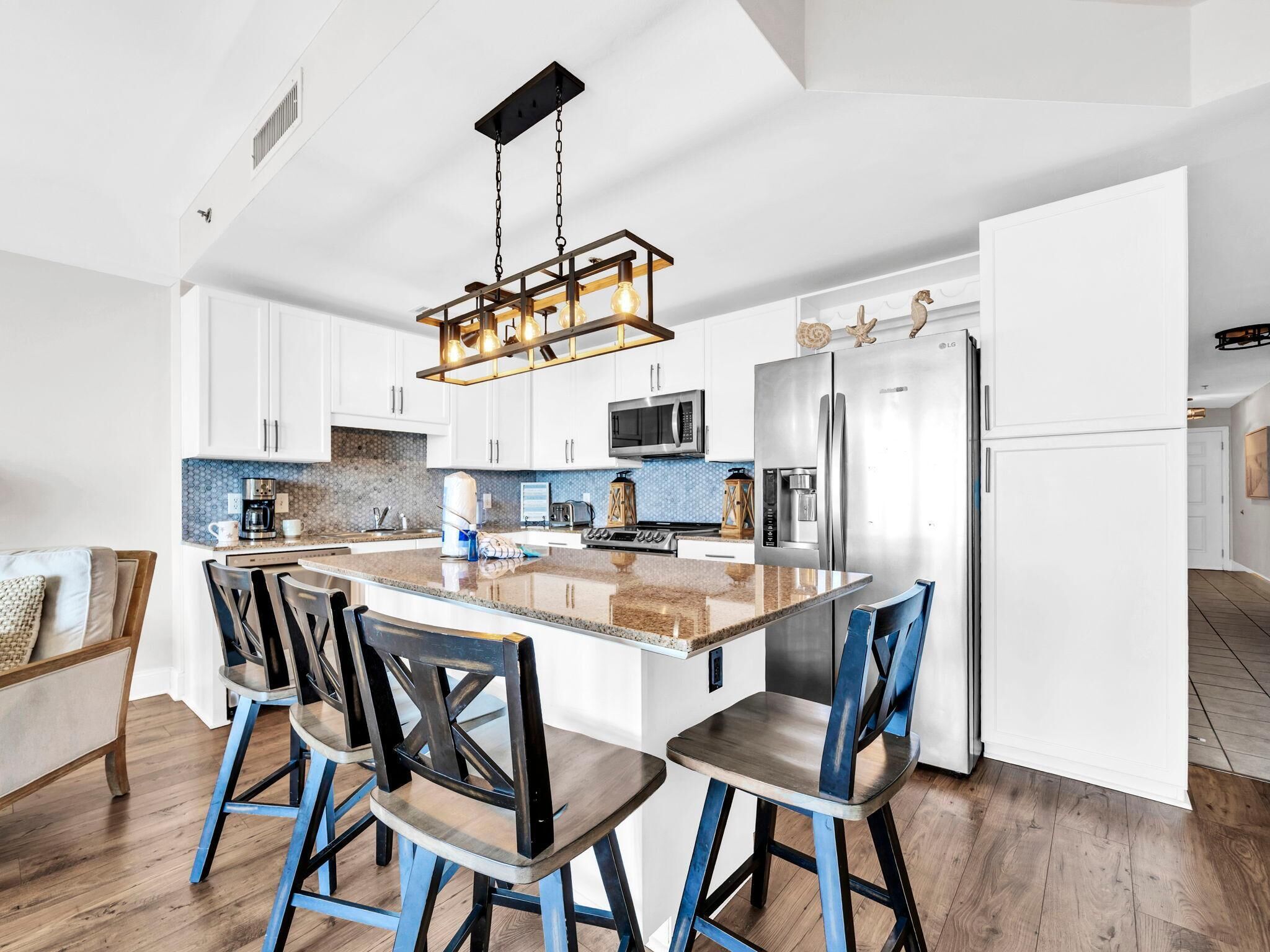 A modern kitchen with white cabinets, a central island, and a stainless steel refrigerator.