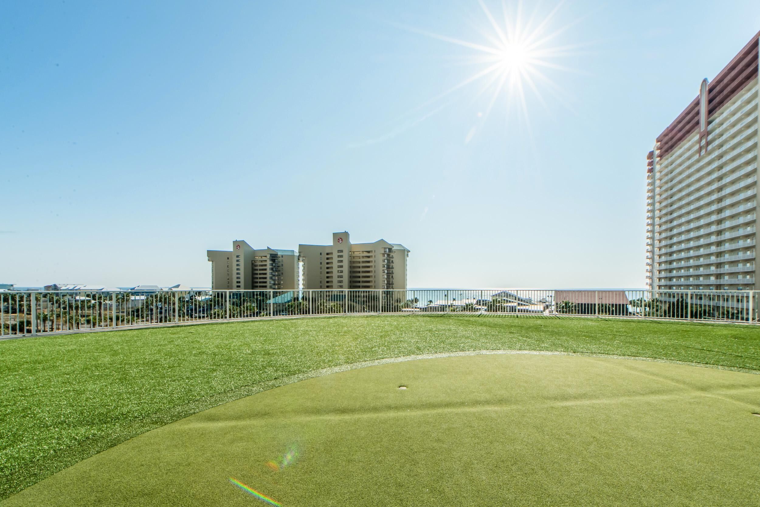 A golf course with a clear sky and buildings in the background.