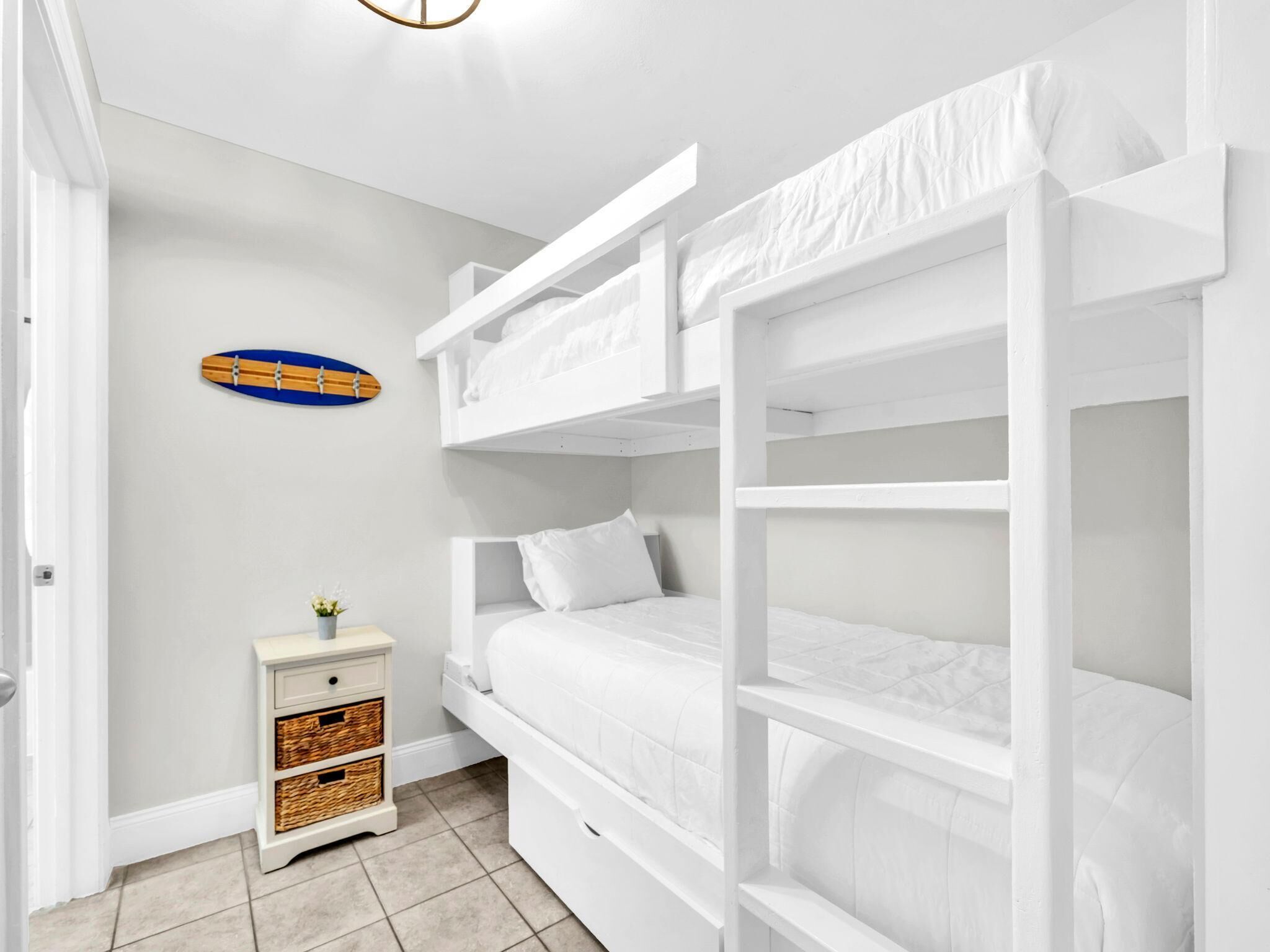 Habitación con literas, una mesita de noche pequeña y una decoración con una tabla de surf.